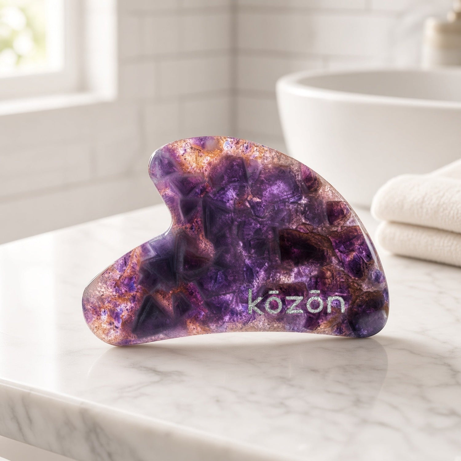 Kōzōn Amethyst Face Gua Sha on a marble bathroom counter